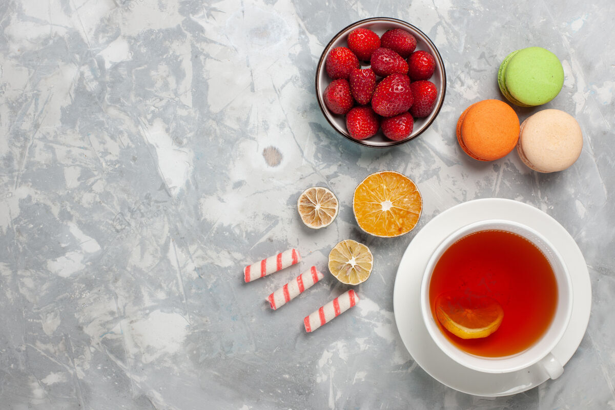 饼干顶视图一杯茶 白色表面有新鲜的红色草莓和法国马卡龙派健康维生素