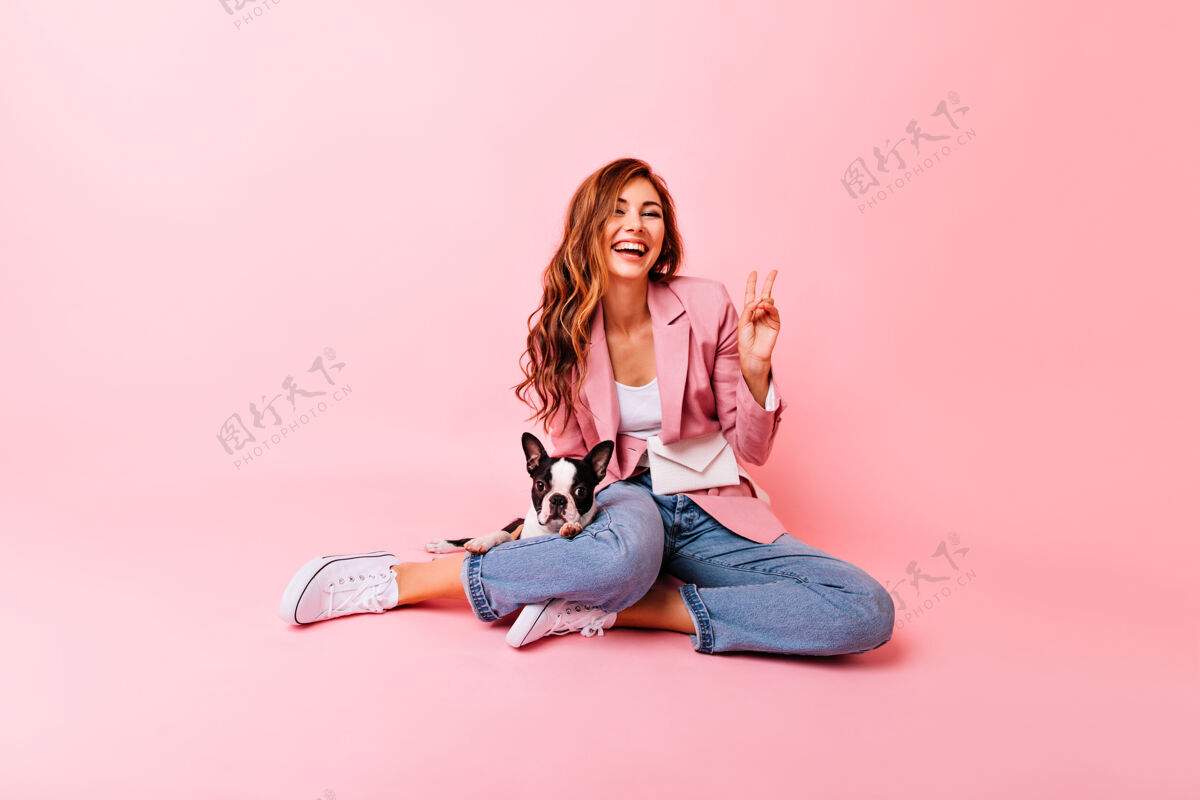 女人可爱的女孩摆出和平的姿势 和她的狗坐在地板上红发高兴的女人和小狗玩耍的肖像高兴女性休息