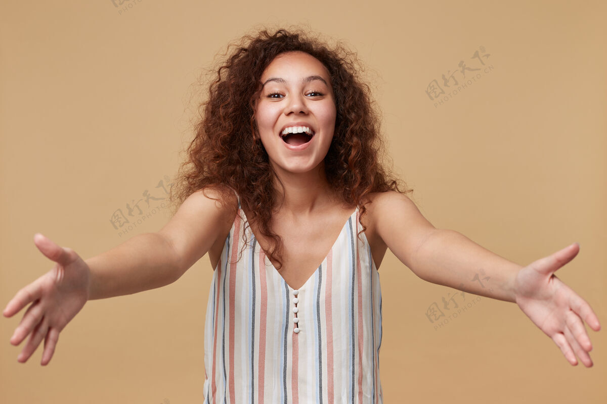 皮带这是一幅年轻漂亮 快乐的棕色卷发女性的画像 她双手张开 面带喜悦地看着米色的头发喜悦拥抱长