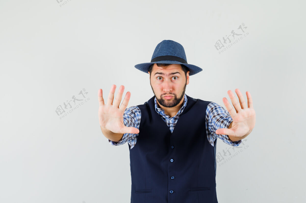 男性穿着衬衫 背心 帽子的年轻人表现出拒绝的姿态 看上去很害怕背心休闲手势