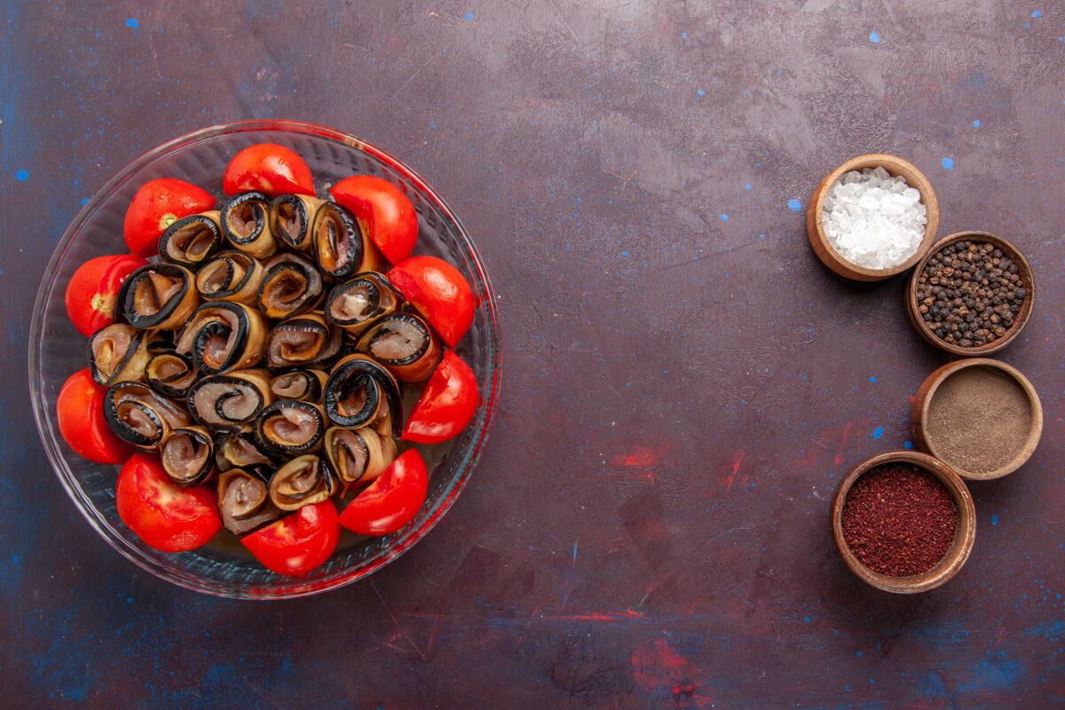 西红柿俯瞰蔬菜餐切片和卷西红柿与茄子和调味品在深紫色的背景西红柿蔬菜烹饪