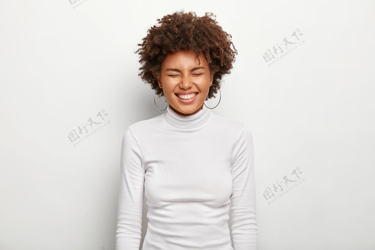 休闲快乐的非洲女性的横向肖像 笑得很大声 闭着眼睛 心情很好 穿着高领毛衣 孤立在白墙上人 满足 快乐 民族 情感欢呼模特年轻
