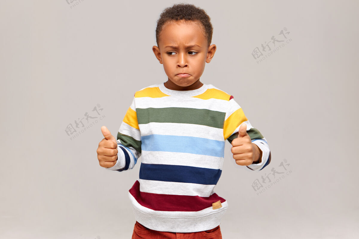 非洲穿着条纹套头衫的有趣的非洲裔小男孩摆出竖起大拇指的姿势 说干得好 称赞某人工作出色 学习或工作成功黑人孩子赞成肖像表情微笑