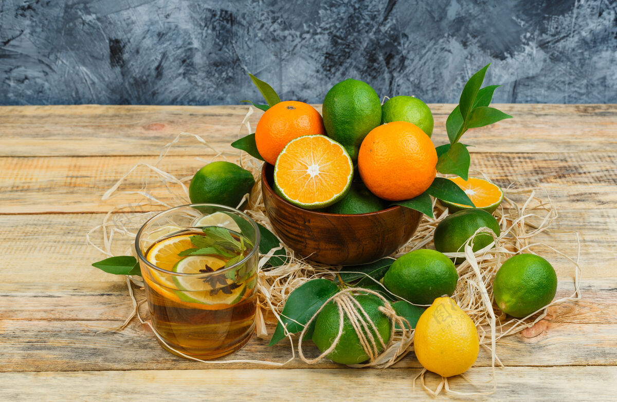 树叶柑橘类水果和凉茶在木板和蓝色大理石表面锅甜角度自然