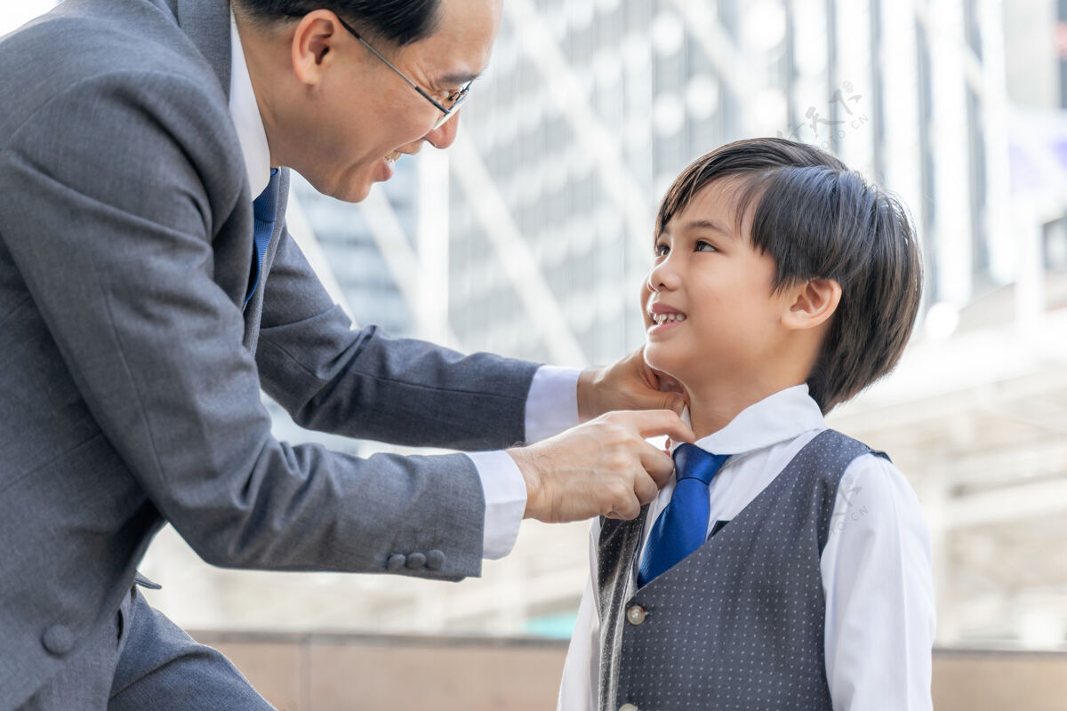 快乐父亲在市区商业区为儿子做了西装领子团结爸爸家庭