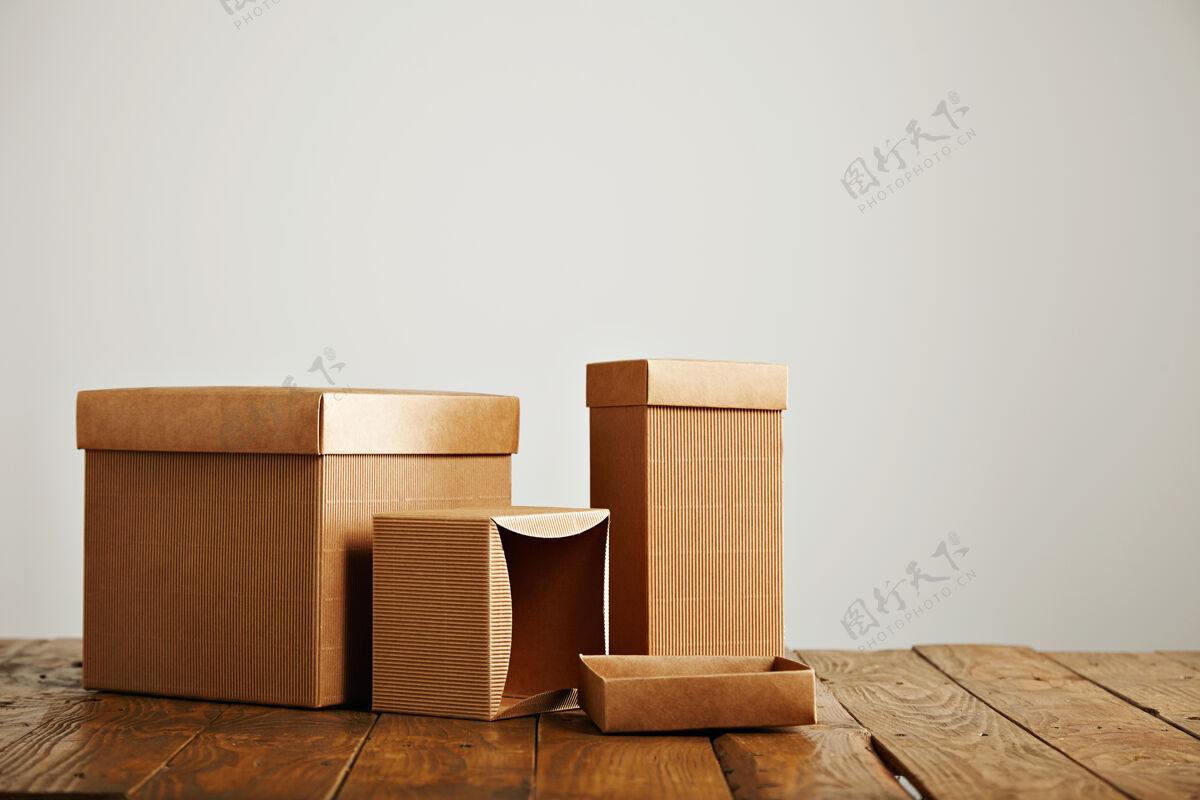 瓦楞在一张不平整的木桌上 不同形状和大小的未贴标签的类似盒子被隔离在白色的地板上封闭包装包装机