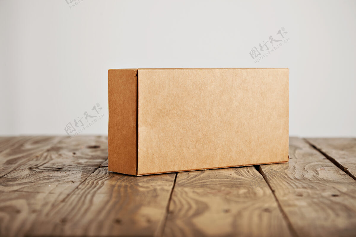空的工艺无标签纸板包装盒呈现在强调拉丝木桌上 隔离在白色背景上消费主义打开礼品