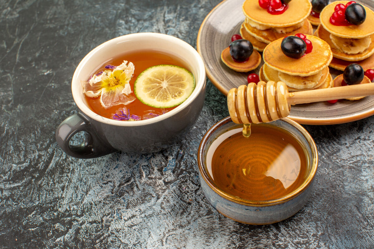 餐厅特写镜头的经典美国煎饼与蜂蜜和一杯茶健康营养杯子