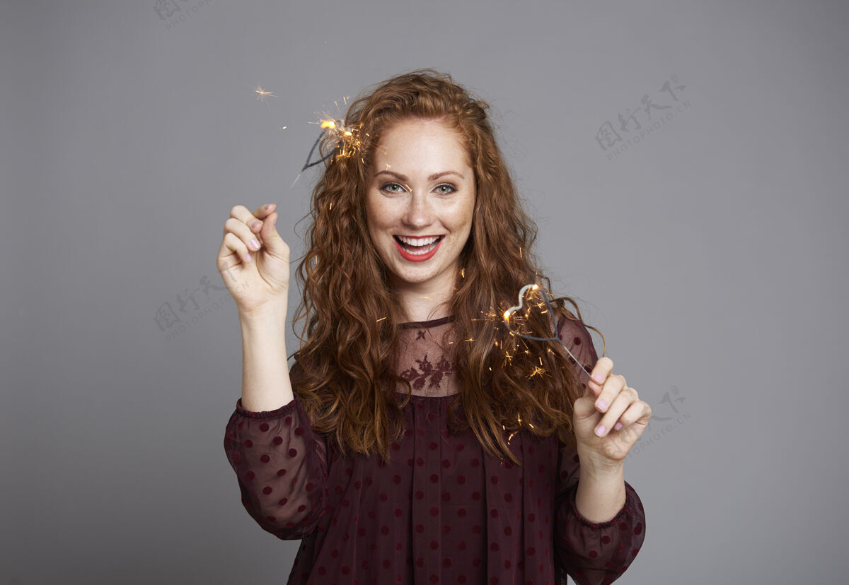 燃烧在摄影棚拍摄的带着燃烧的火花的快乐女人的肖像站立幸福优雅