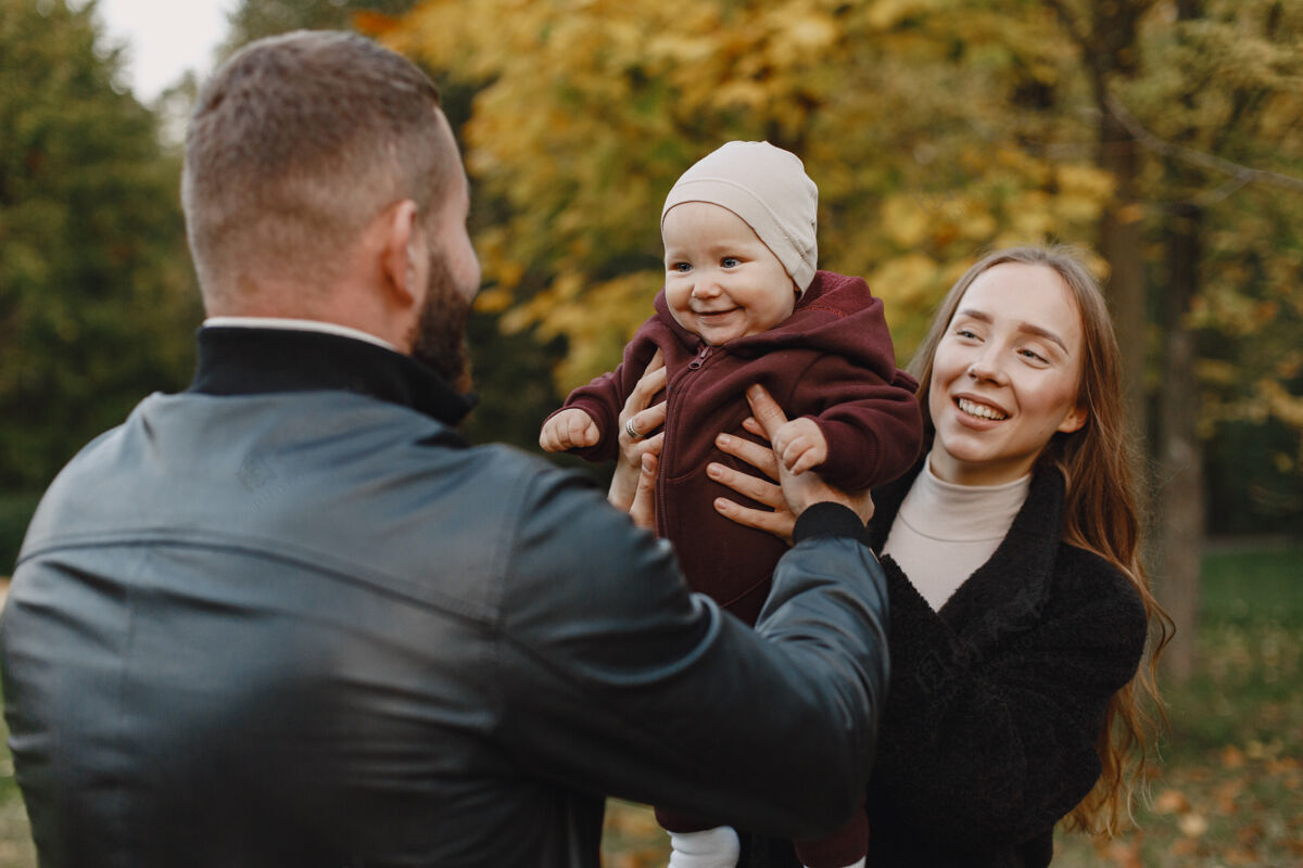 公园一家人在秋天的公园里男人穿着黑色夹克可爱的小女孩和父母男性家庭快乐