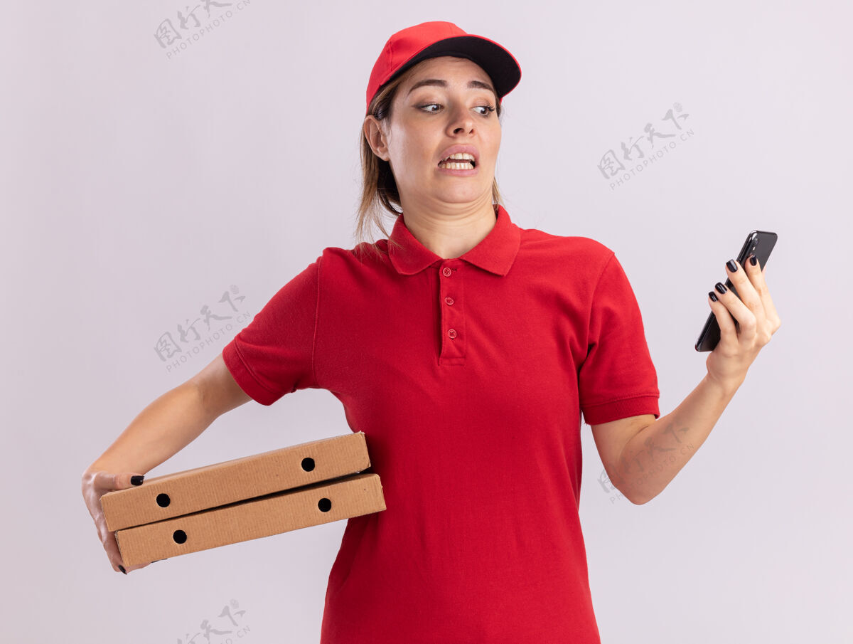 制服焦急的年轻漂亮的女送货员穿着制服拿着比萨饼盒 看着电话焦虑女人表情
