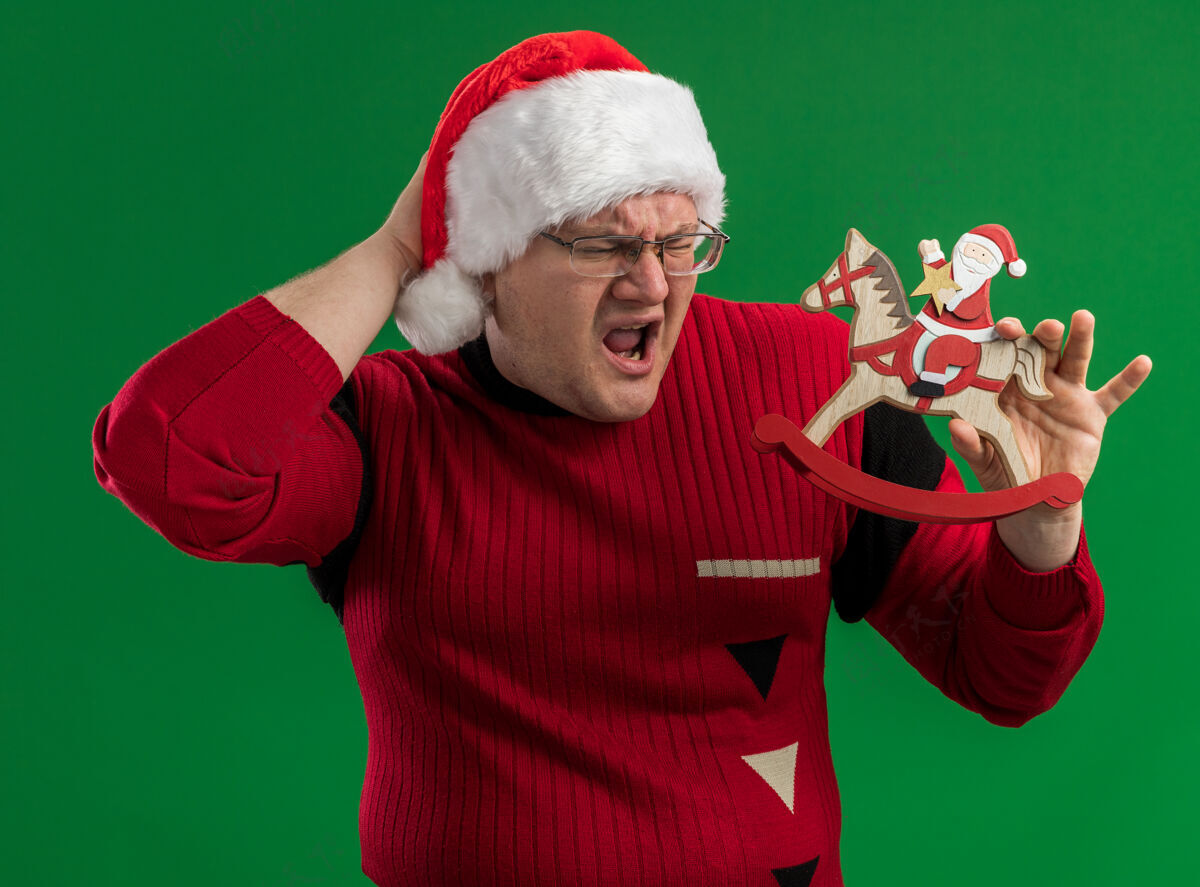 头痛戴着眼镜 戴着圣诞帽 手放在脑后 手放在头上 手放在摇摇木马上的圣诞老人看着它 在绿色的背景下 他头痛得要命保持快乐帽子