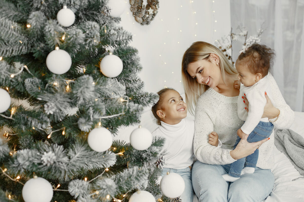 闪亮人们在为圣诞节做准备母亲在和女儿们玩耍一家人在节日的房间里休息孩子穿着毛衣家毛衣室内