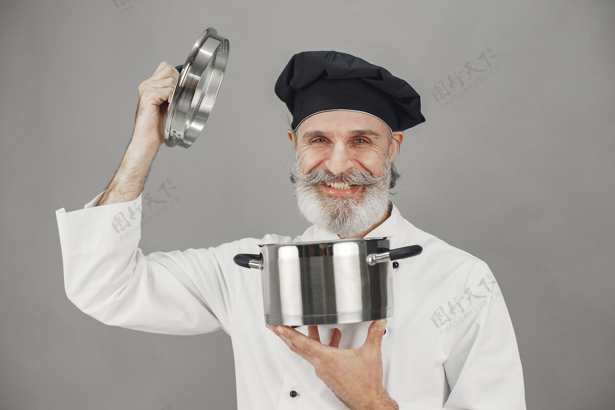 烹饪高级男子与金属锅厨师在一个黑色的帽子专业的方法来处理业务厨房人工人