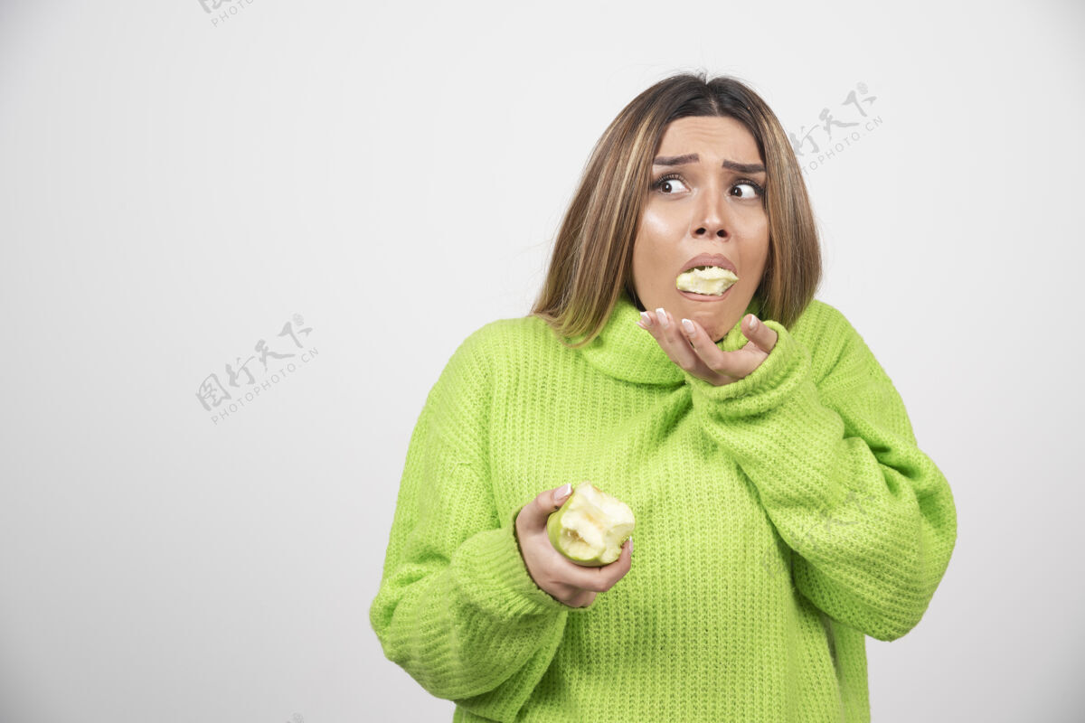 苹果穿着绿色t恤的年轻女子正在吃苹果吃水果肖像