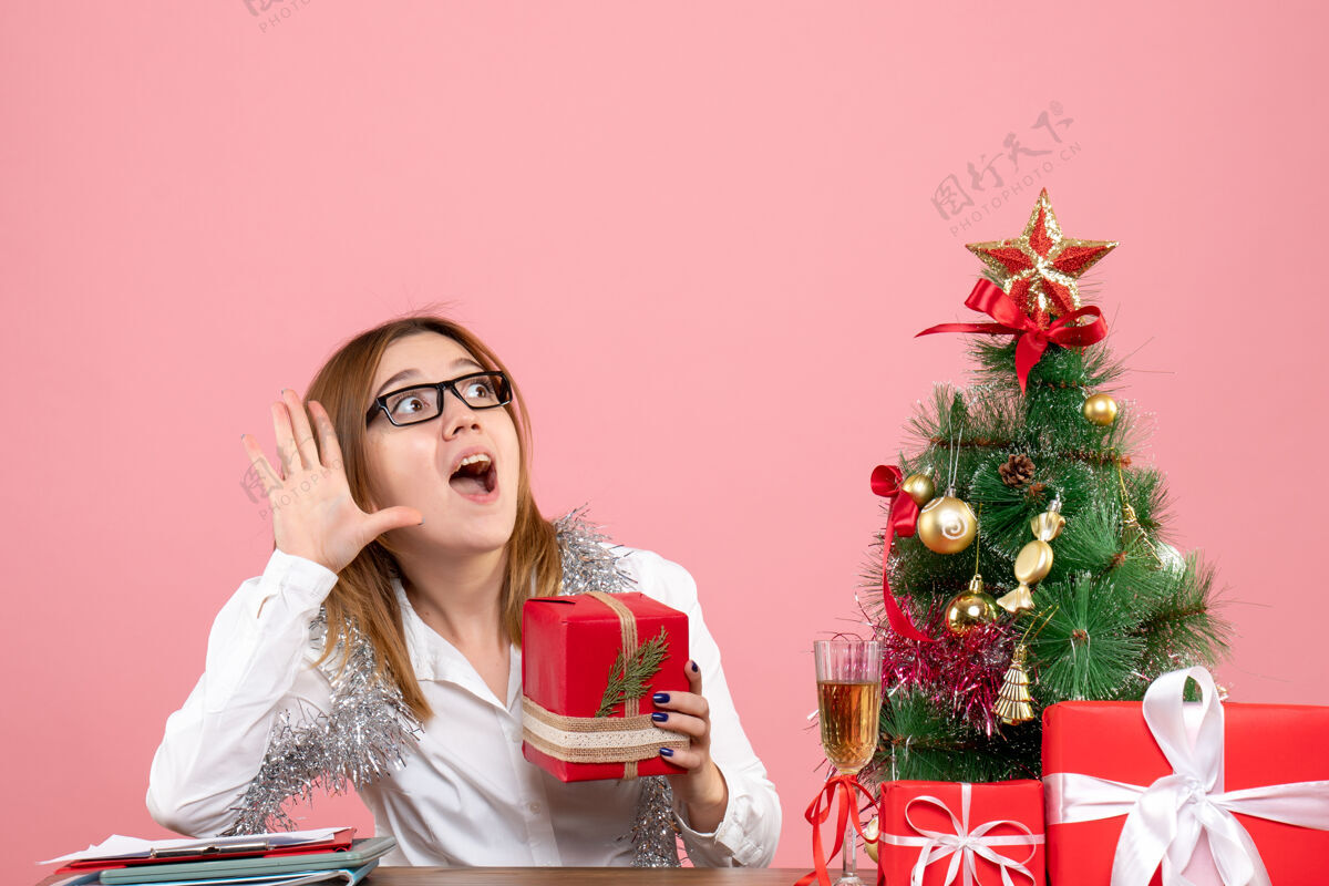 礼物女工正坐在粉红色的椅子上 手里拿着圣诞礼物工作人们坐着