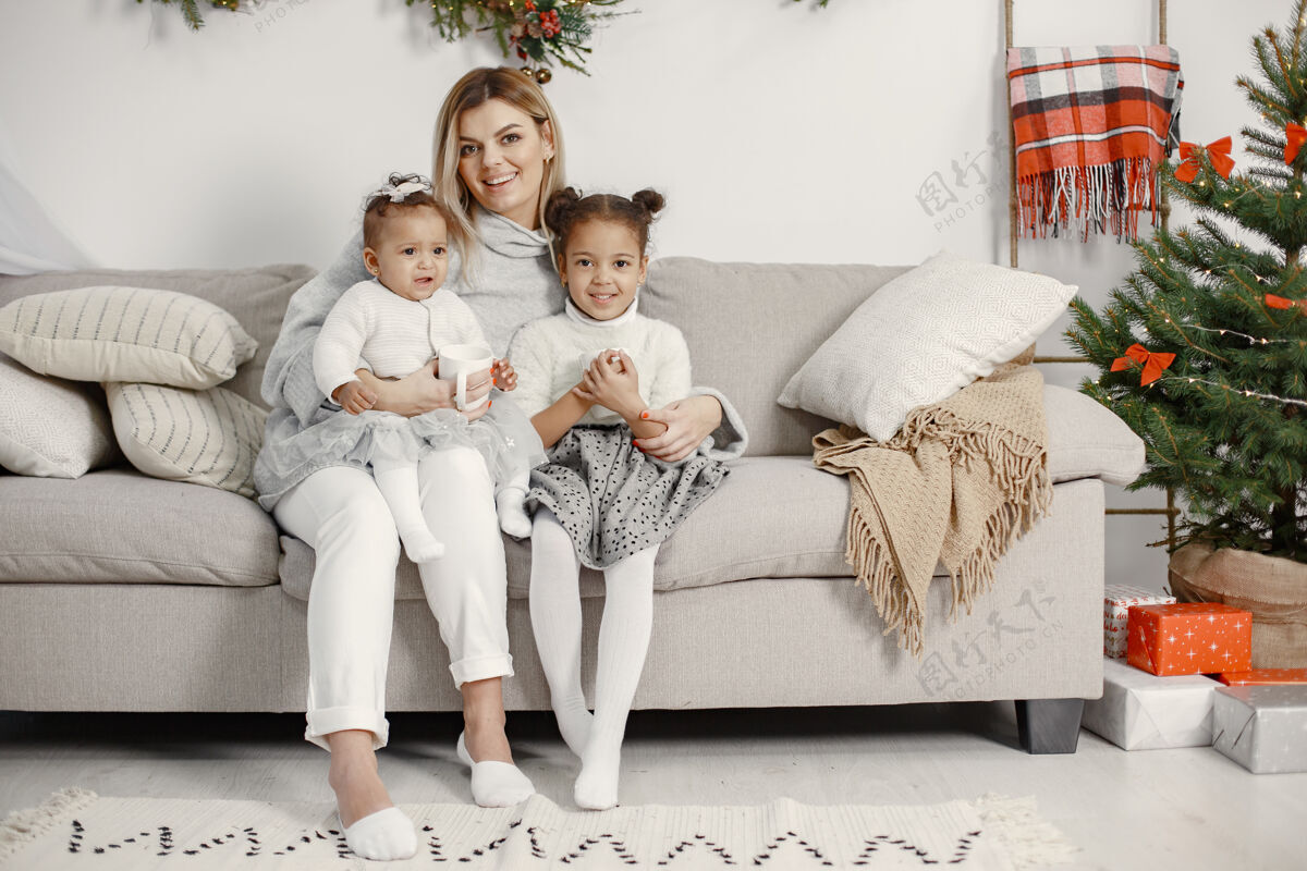 茶人们在为圣诞节做准备母亲在和女儿们玩耍一家人在节日的房间里休息孩子穿着毛衣姐妹美国花环