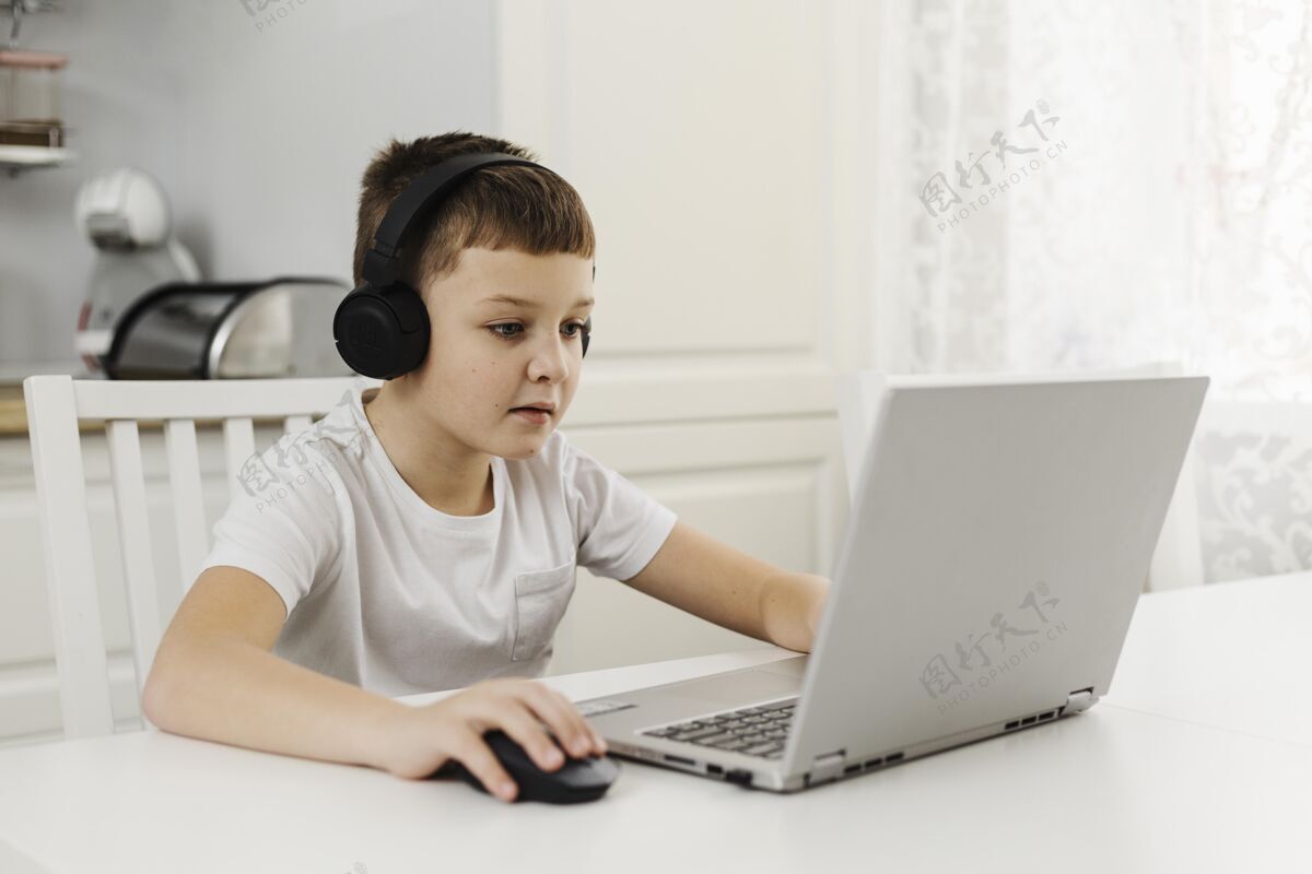 男性男孩在家里玩笔记本电脑和戴耳机房子科技男孩