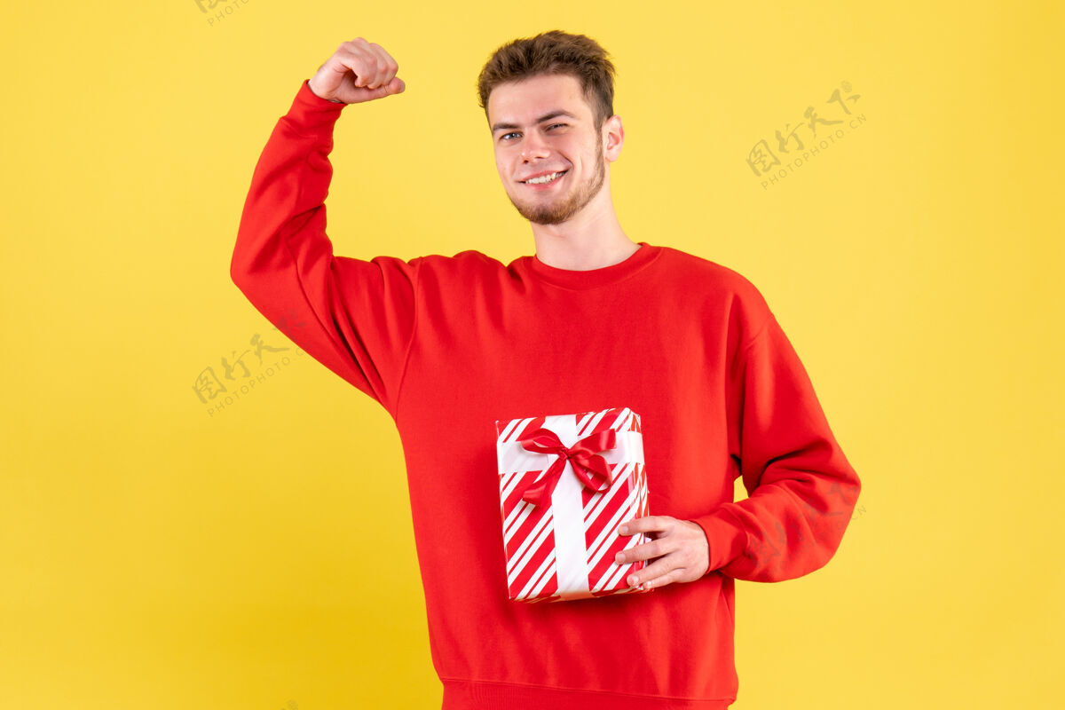 情感正面图：穿着红色衬衫的年轻男性 带着圣诞礼物圣诞节雪礼物