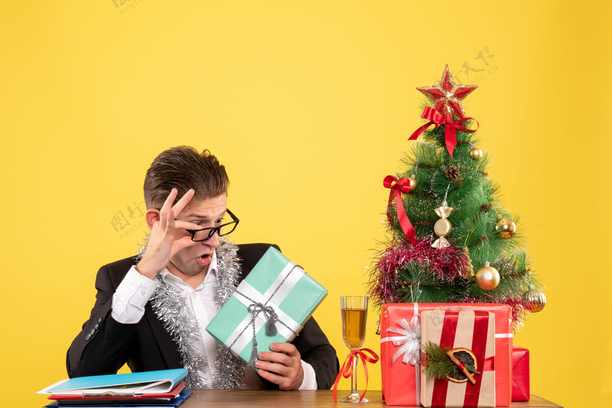 树正面图：男工人拿着圣诞礼物和圣诞树坐着男情感工作