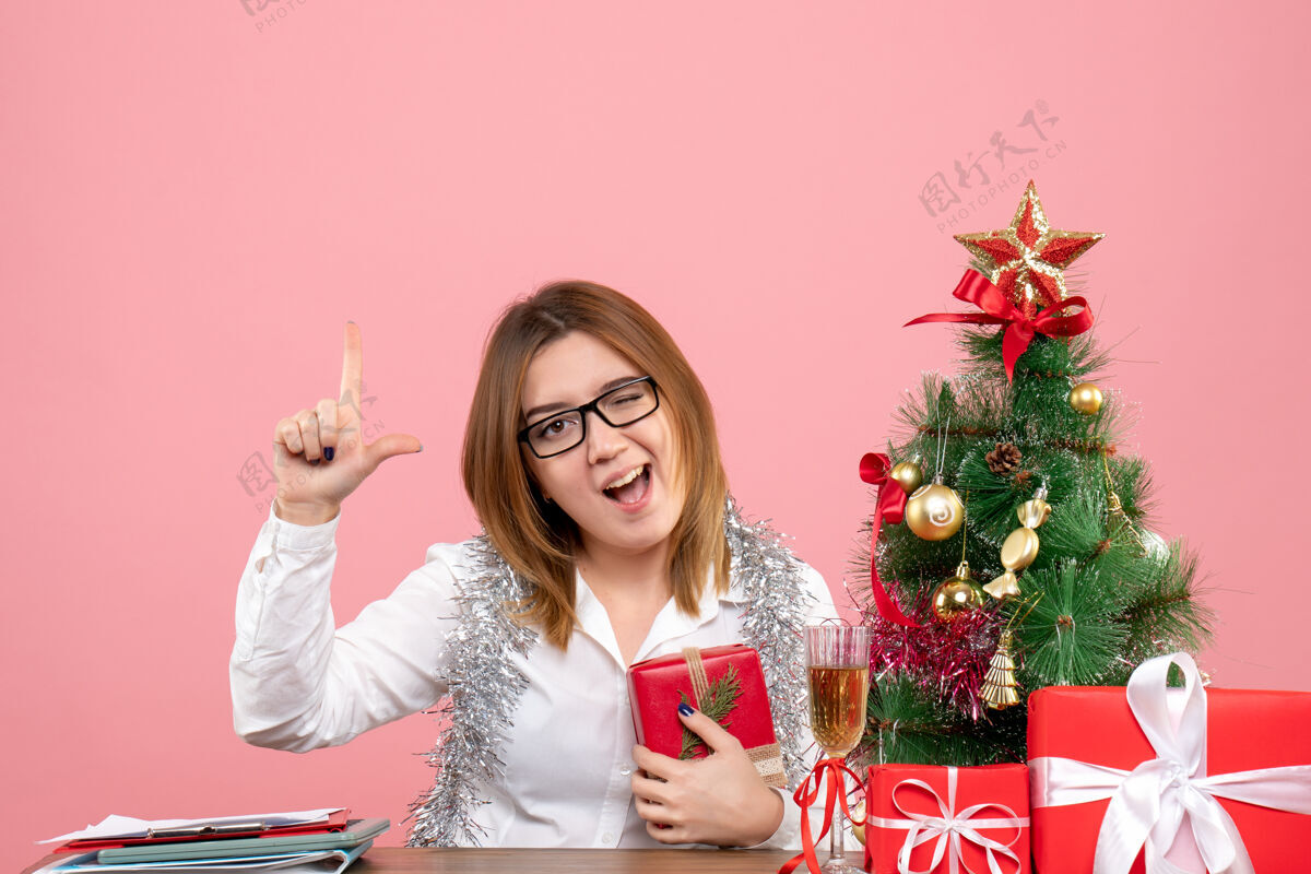 坐着女工正坐在粉红色的椅子上 手里拿着圣诞礼物工作情感礼物