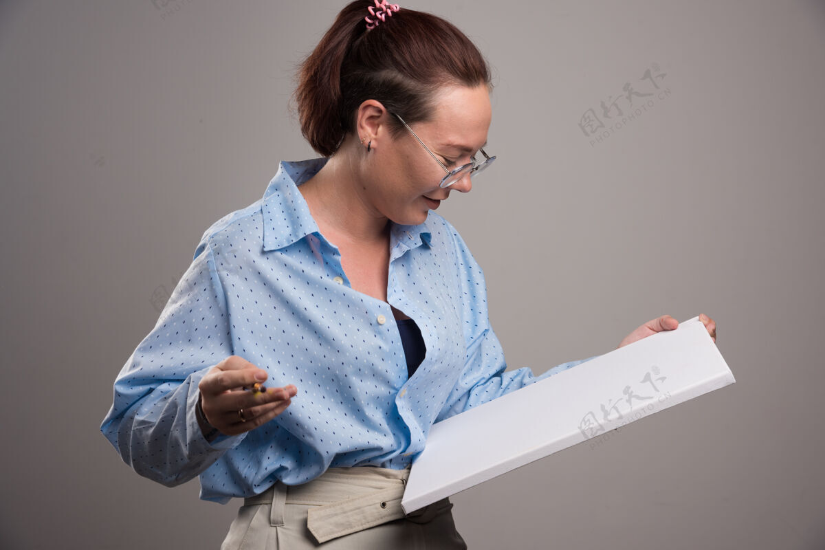 女孩女人看着空画布和灰色背景上的画笔纸板画布