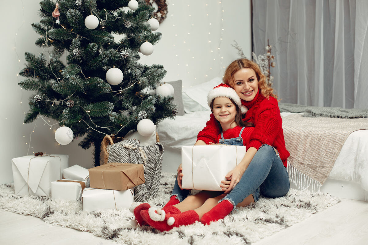 面纱人们在为圣诞节做准备母亲在和女儿玩耍一家人在节日的房间里休息孩子穿着红色毛衣女人毛衣装饰