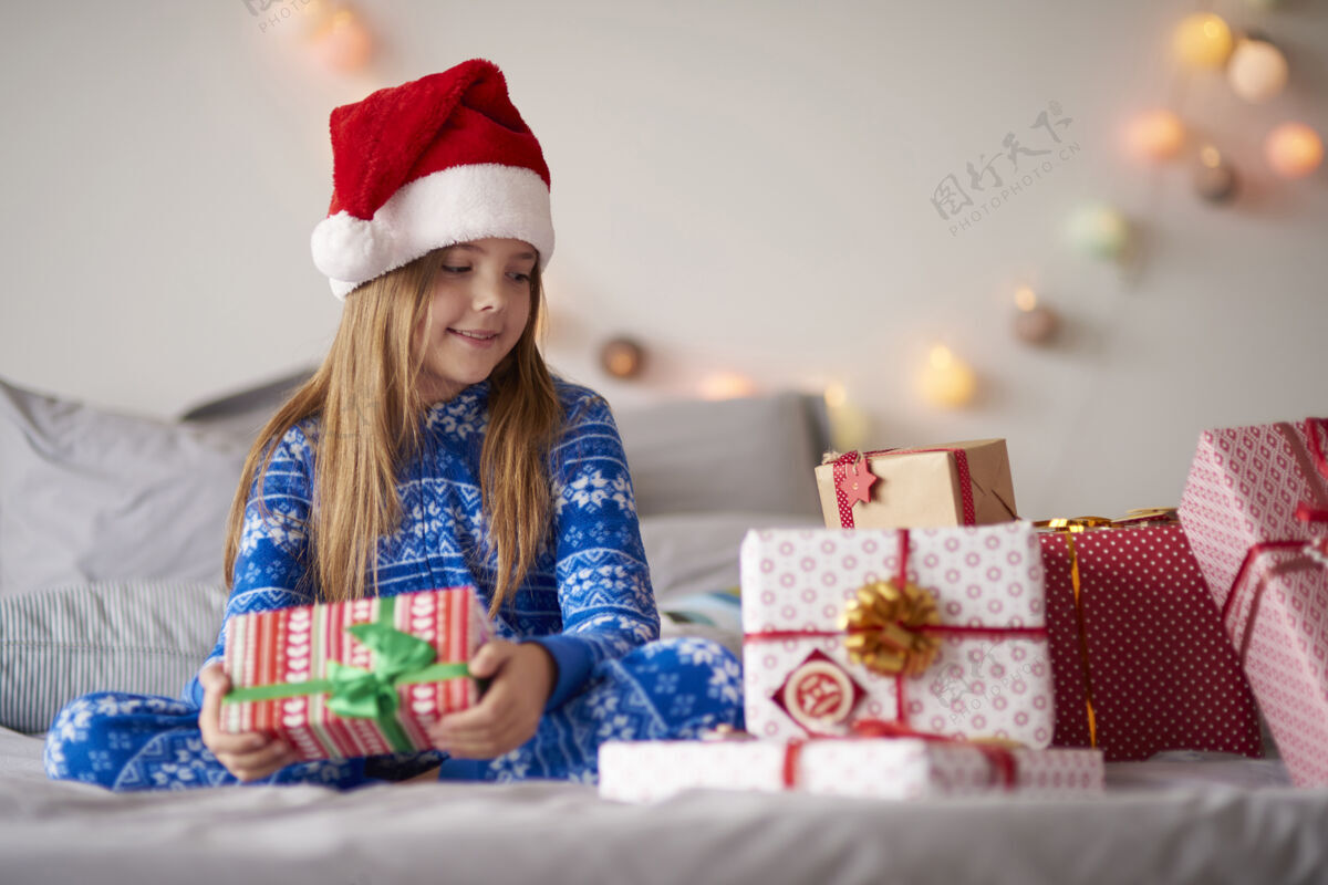 礼物可爱的小女孩在床上拿着圣诞礼物圣诞老人盒子孩子