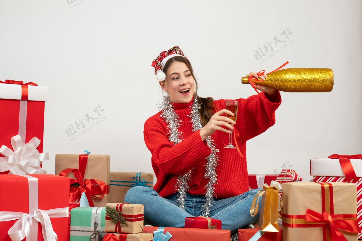 女孩戴着圣诞帽 倒香槟的快乐派对女孩围坐在白色的礼物旁礼物卖家快乐