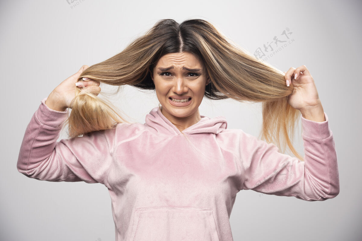 女性穿着粉色运动衫的金发女士对自己的干枯头发或发色感到不满意金发粉色头发