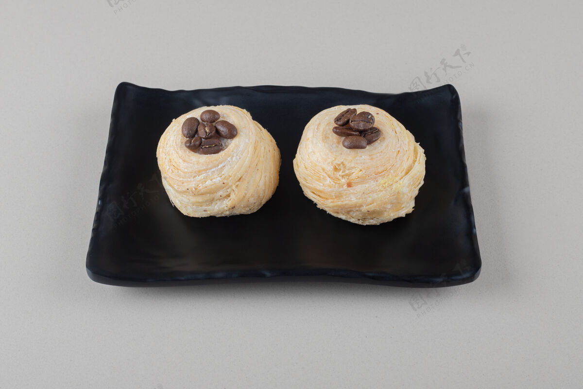 好吃的在大理石背景的盘子上放上咖啡豆馅的片状蛋糕烤的糕点片状的
