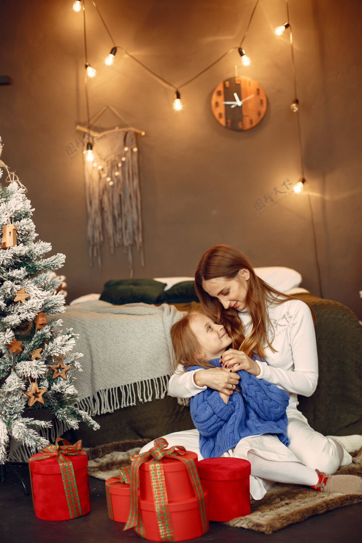 毛衣人们在为圣诞节做准备母亲在和女儿玩耍一家人在节日的房间里休息孩子穿着蓝色毛衣女人蓝色面纱