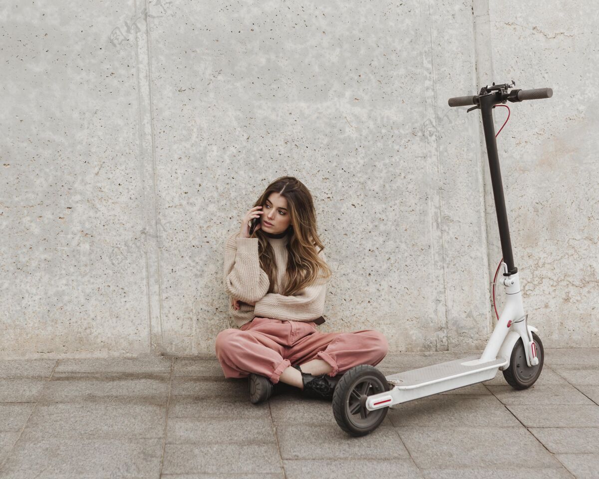 交通一个年轻的女人和一辆电动滑板车摆姿势女人城市交通骑手