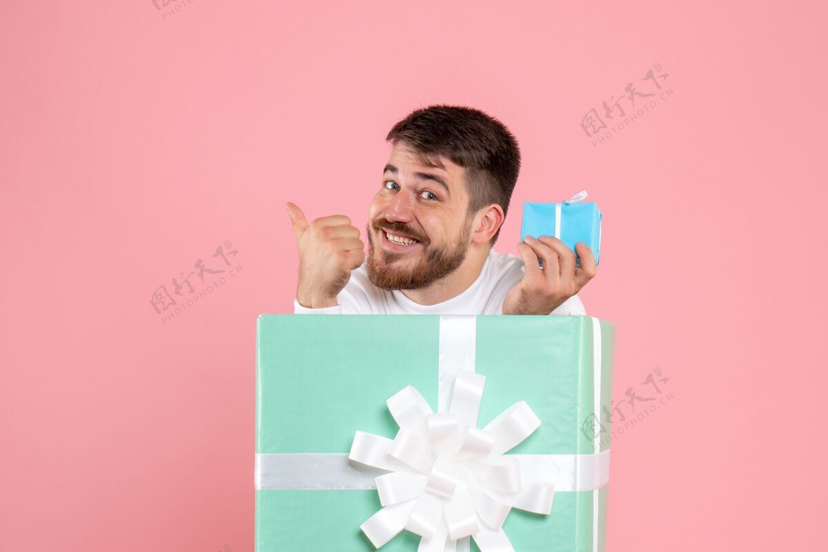 男性礼物盒内年轻人的正面图 粉红色的墙上挂着小礼物年轻盒子情感