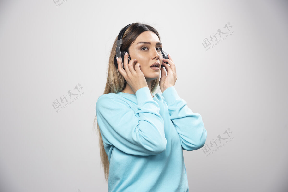 雇员金发dj女孩用耳机听音乐 不喜欢困惑成人不满意