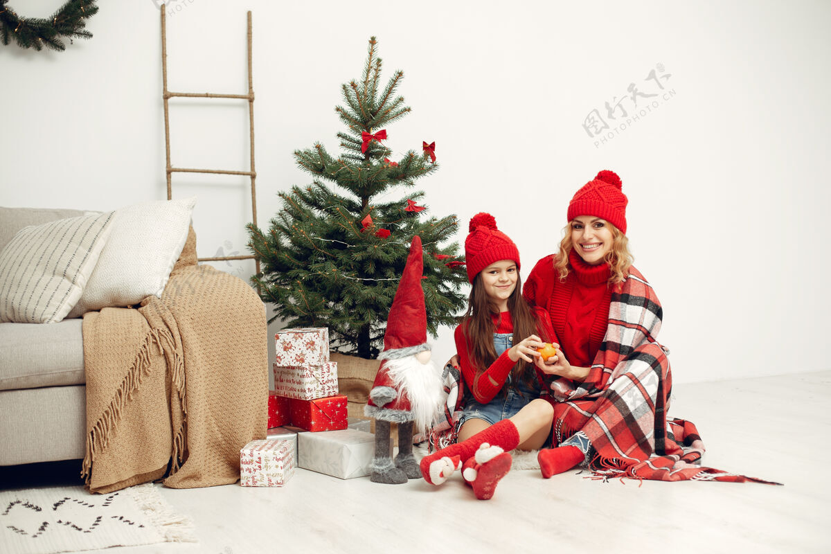孩子人们在为圣诞节做准备母亲在和女儿玩耍一家人在节日的房间里休息孩子穿着红色毛衣亮光童年母亲