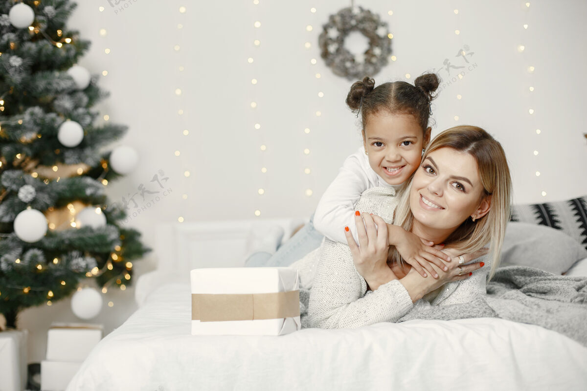 女人人们在为圣诞节做准备母亲在和女儿玩耍一家人在节日的房间里休息孩子穿着毛衣杉木孩子面纱