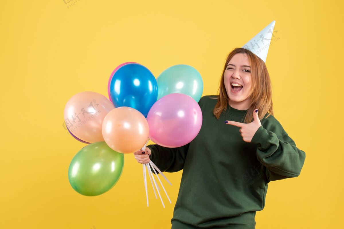 乐趣正面图：带着彩色气球的年轻女性年女性节日