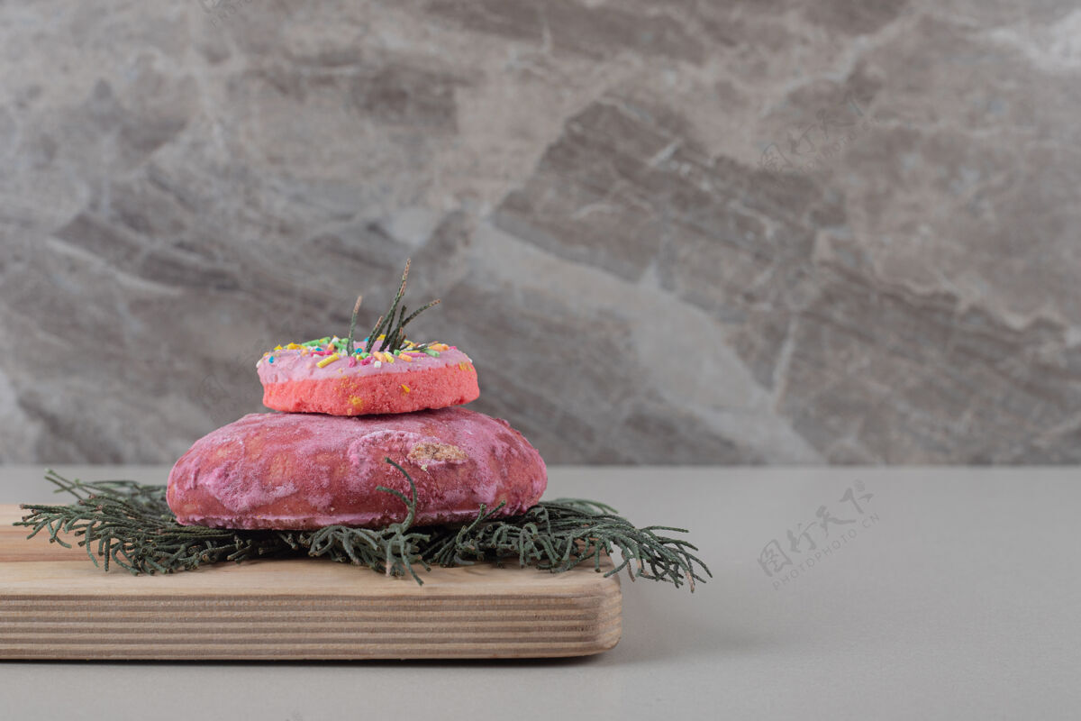 叶小甜甜圈放在松叶饼干上 放在大理石背景板上板甜点香料