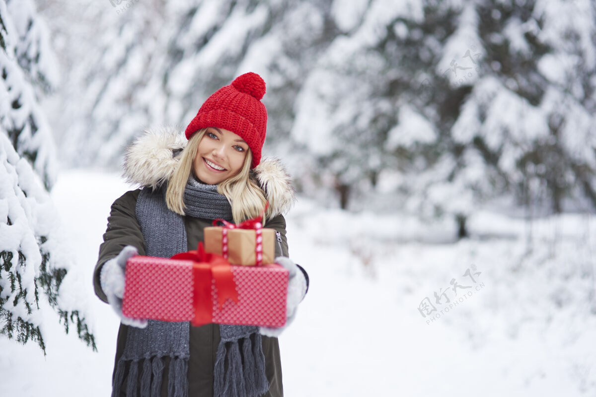 女人微笑的女人送两份圣诞礼物的画像针织帽美丽户外
