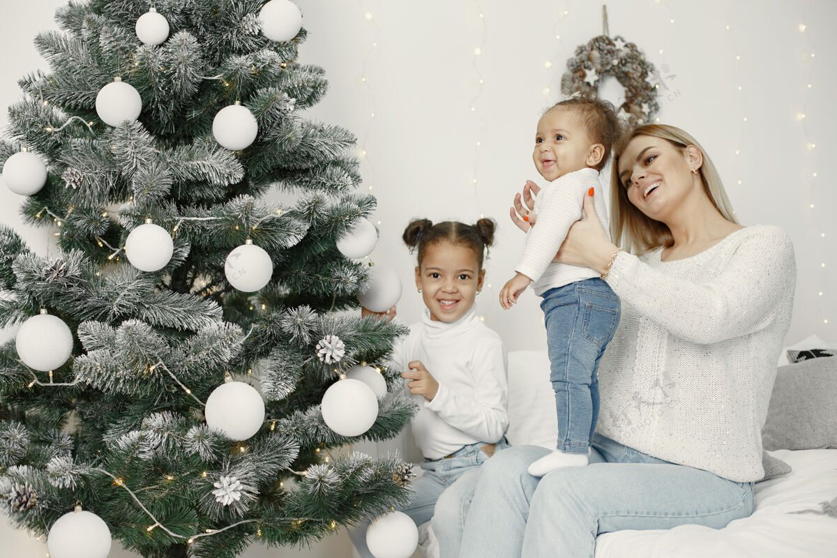 母亲人们在为圣诞节做准备母亲在和女儿们玩耍一家人在节日的房间里休息孩子穿着毛衣国际童年装饰