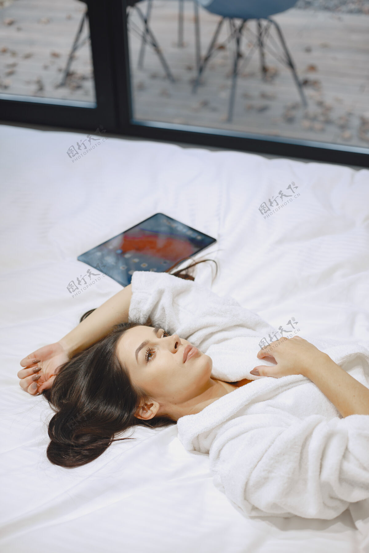 治疗早上好床上的女人卧室里的女人拿着药片的黑发女人头发平板电脑卧室