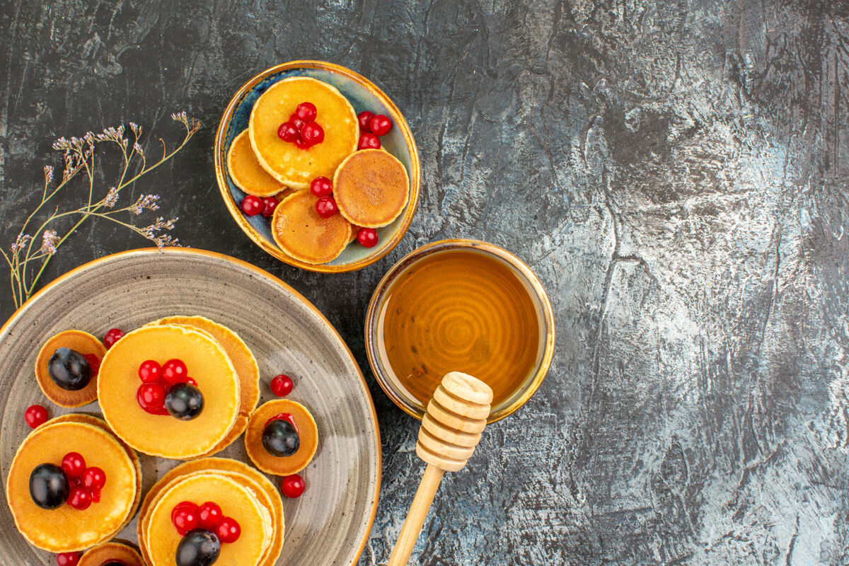 刷子用蜂蜜放在一个大大小小的盘子里 近距离观看美味的煎饼棍子勺子蜂蜜