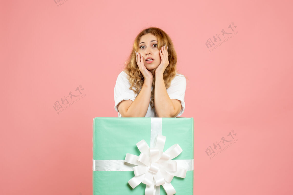 年轻女性正面图：站在蓝色礼品盒内的年轻女性节日粉色丝带
