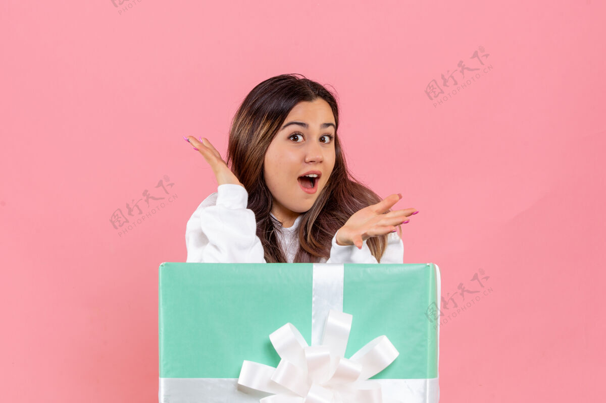 女性站在粉红色墙上的年轻女子的正视图庆祝商务圣诞快乐