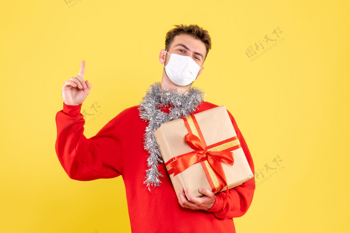 年正面图：戴着无菌面具的年轻男性正在过圣诞节不育流行性颜色