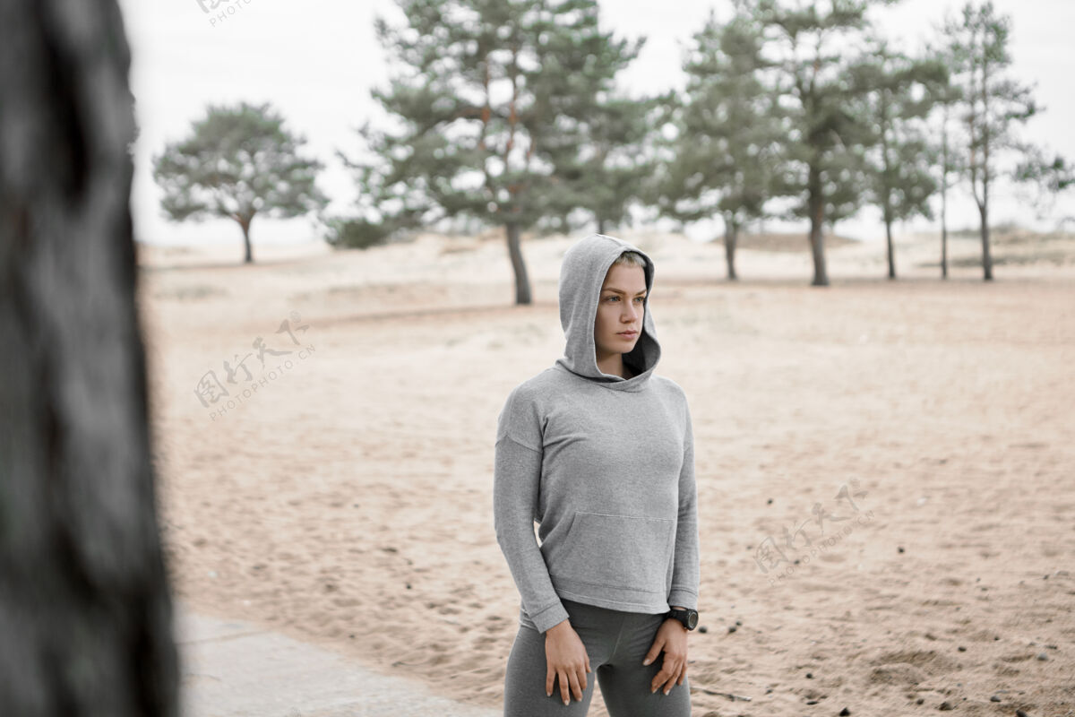 运动户外图片：身材苗条的年轻女子穿着时尚的运动服 在沙滩和松树的背景下 在户外摆姿势 锻炼身体 做晨练选择重点运动健身健康