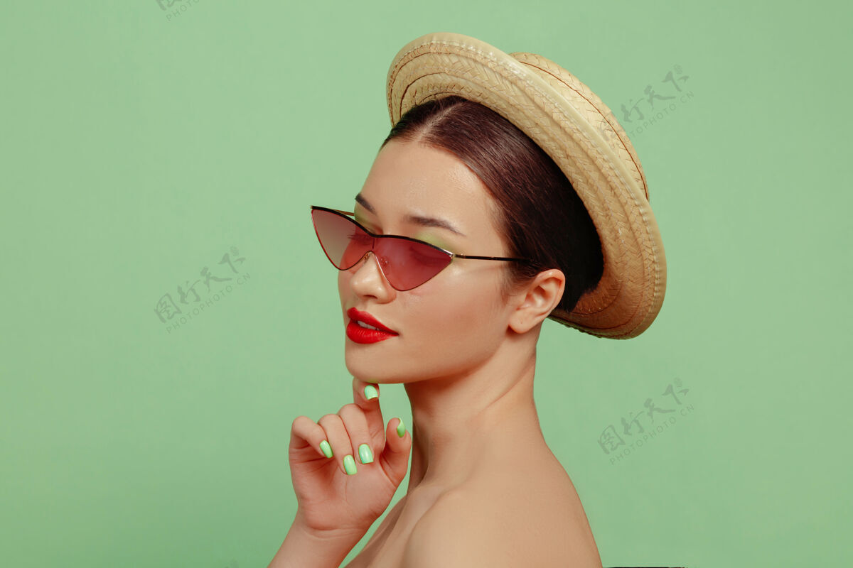 自信美丽女人的肖像 明亮的妆容 红色的眼镜和帽子时髦和时尚的制作和发型夏天的颜色摆姿势明亮人类女性