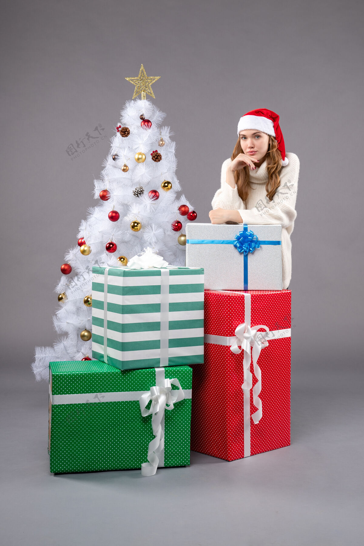 礼物周围的年轻女性圣诞礼物灰色地板节日圣诞礼物圣诞树礼物地板
