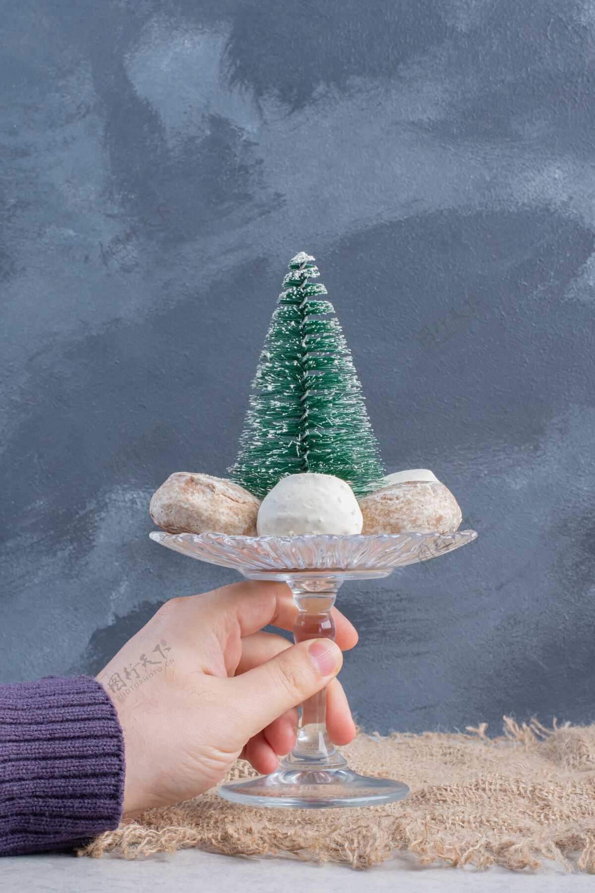 糖饼干围绕着一个树雕像在一个小基座上 由一只手在大理石表面举行甜小吃可口